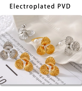 Detailed macro view of pearl clover rings and silver earrings on a shell tray