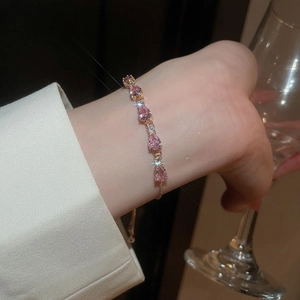 Detail showing pink teardrop zircon stones on adjustable gold bracelet with micro-pave