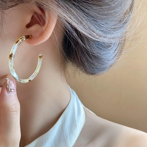 Detail of amber tortoiseshell resin C-shaped hoop earring worn on model profile