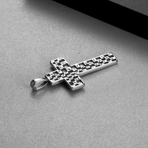 Macro shot of silver stainless steel cross pendant with checkered texture and vintage finish