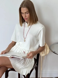 Schickes weißes Kurzarm-Strick-Polo und Faltenrock-Set für Damen in Sitzposition
