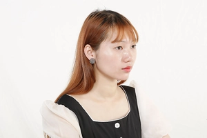 Close-up of vintage silver hollow patterned round stud earring worn by female model