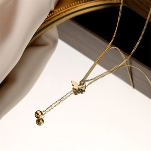 Détail du collier papillon doré avec perles à franges sur une surface réfléchissante