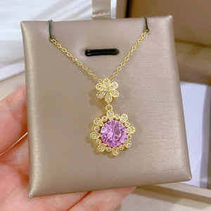 Detailed shot of a gold necklace featuring a pink floral pendant with sparkling diamonds