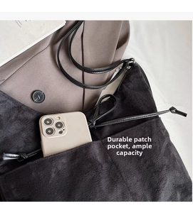 Close-up of black plush shoulder bag featuring a functional front pocket for smartphone storage