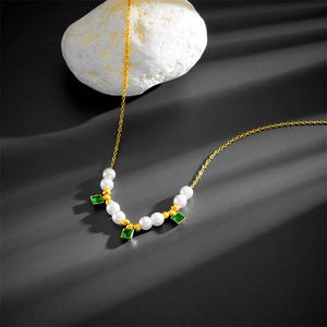 Detail of double-layer necklace with white pearls and three green square gemstone pendants