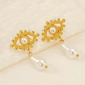 Close-up of golden Evil Eye earrings with woven texture, small pearls, and baroque drops