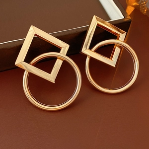 Détail de boucles d'oreilles dorées géométriques avec losange et cercle entrelacés