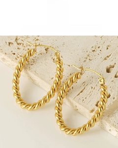 Close-up of 18K vacuum gold-plated oval twist earrings on natural stone background