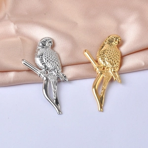 Detail of bird shaped pins in gold and silver finish on soft pink silk background