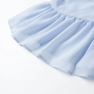Dettaglio dell'orlo con volant azzurro e consistenza a pieghe morbide della camicia
