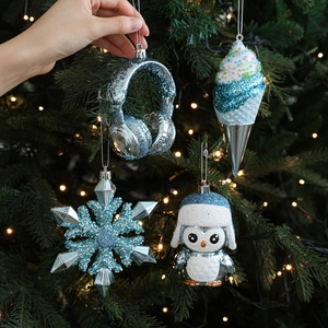 Blue and silver Christmas ornaments set with snowflake and penguin hanging on festive tree