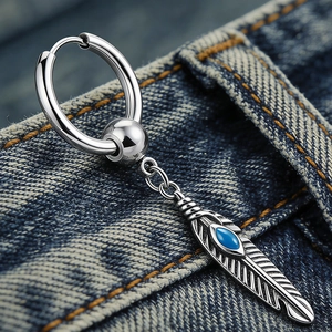 Dettaglio dell'orecchino a piuma d'argento con pietra blu su tessuto di jeans
