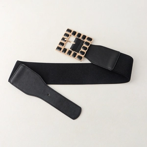 Detail of black elastic waist belt featuring a gold square buckle with black acrylic inlay