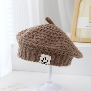 Dettaglio del berretto in maglia marrone per bambini con trama a nido d'ape