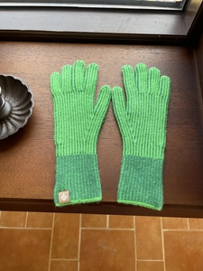 Detalle de textura de punto de guantes táctiles verde brillante con etiqueta de cuero