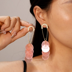 Detail of pink shell-like resin discs and gold rhinestones on long geometric earrings