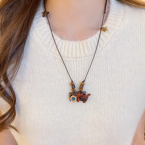Detailed view of handmade wooden camera and cat pendant on a stylish brown cord necklace