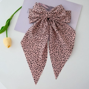 Detail of large leopard print bow hair clip with ribbons on a soft lavender background