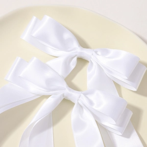 Detailed close-up of double-layered white satin ribbon bows with elegant long streamers