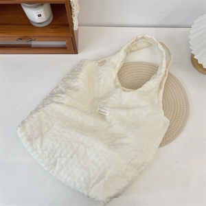 Detail of Sozakka label on ivory textured canvas tote bag with woven fabric surface