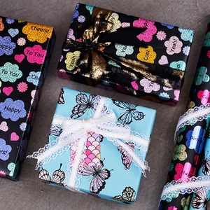 Vibrant laser floral gift wrapping paper with glitter finish and decorative ribbons