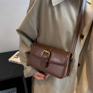 Retro brown wax leather crossbody bag with gold buckle shown on a stylish casual model