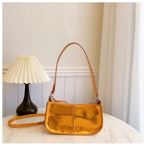 Détail de sac bandoulière en cuir PU orange métallisé avec œillets punk argentés