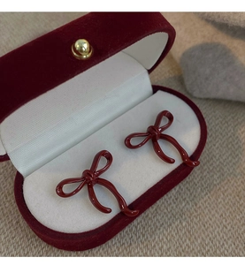 Detail of dark red bow earrings presented in a luxury vintage velvet jewelry box