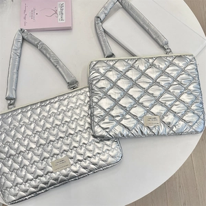 Close-up of silver quilted laptop sleeves with heart and diamond patterns on a desk