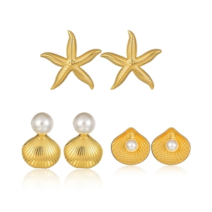 Ensemble de boucles d'oreilles dorées avec étoiles de mer et perles sur fond blanc