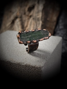 Macro shot of vintage style adjustable ring with raw green tourmaline in rustic bronze setting