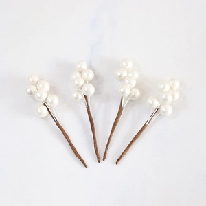 Set of four artificial white berry branches for Christmas decor on marble background
