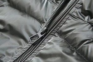 Close-up of high-gloss metallic puffer jacket featuring a black zipper and waterproof fabric