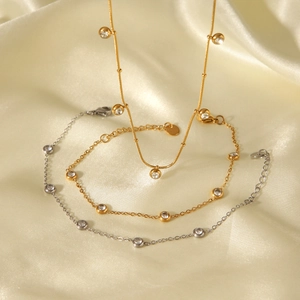 Detail of gold and silver dainty chains with zircon studs on wavy silk fabric