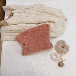 Pink lambskin fleece cosmetic bag with matching hair scrunchies on white bedding