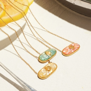 Detail of three gold necklaces with colorful shell pendants and shell charm on white