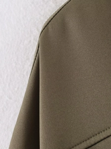 Detailed macro view of military green bomber jacket shoulder with durable woven fabric texture