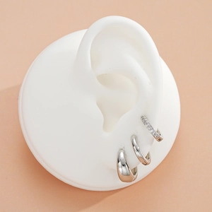 Detailed view of three silver hoop earrings with cubic zirconia on a model ear
