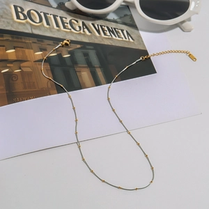 Detailed shot of two-tone minimalist snake chain necklace with gold beads and silver links