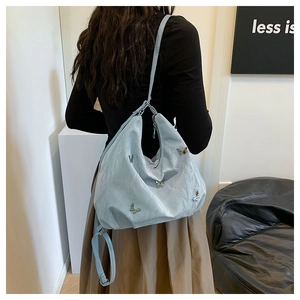 Detail of light blue hobo bag with silver butterfly charms on a soft textured fabric