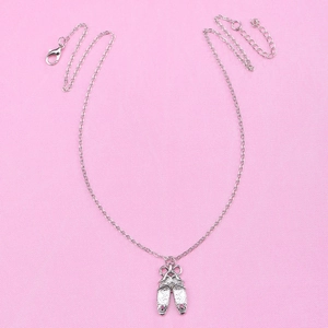 Silver ballet slipper necklace with pink rhinestones on a textured pink background
