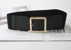 Detail of wide black elastic waist belt with large gold square buckle and leather texture