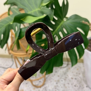 Detail of a large coffee brown glossy bow hair claw clip for high ponytail styling