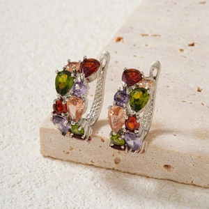 Detailed close-up of silver earrings with multi-color teardrop gemstones on stone base