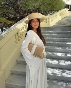 Close-up of a woven straw handbag with white leather detail and a wide-brimmed wool hat