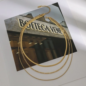 Detailed close-up of a three-layer gold titanium steel necklace featuring figaro and snake chains