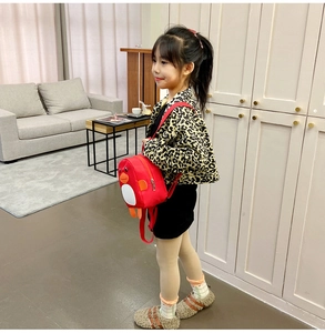 Detail of red cartoon duck backpack for toddler girl shown in a cozy living room setting