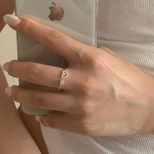 Close-up of a silver heart-shaped zircon ring worn by a model in a casual lifestyle setting