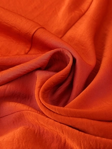 Close-up of orange satin fabric with elegant drapes and smooth texture detail